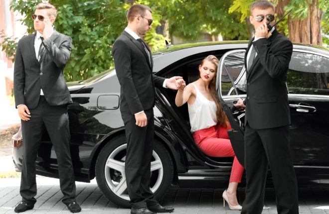 Bodyguard helping young businesswoman to get out of car